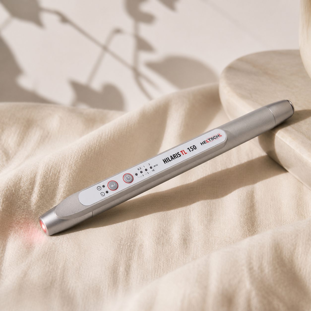 The professional Softlaser device resting on cream linen